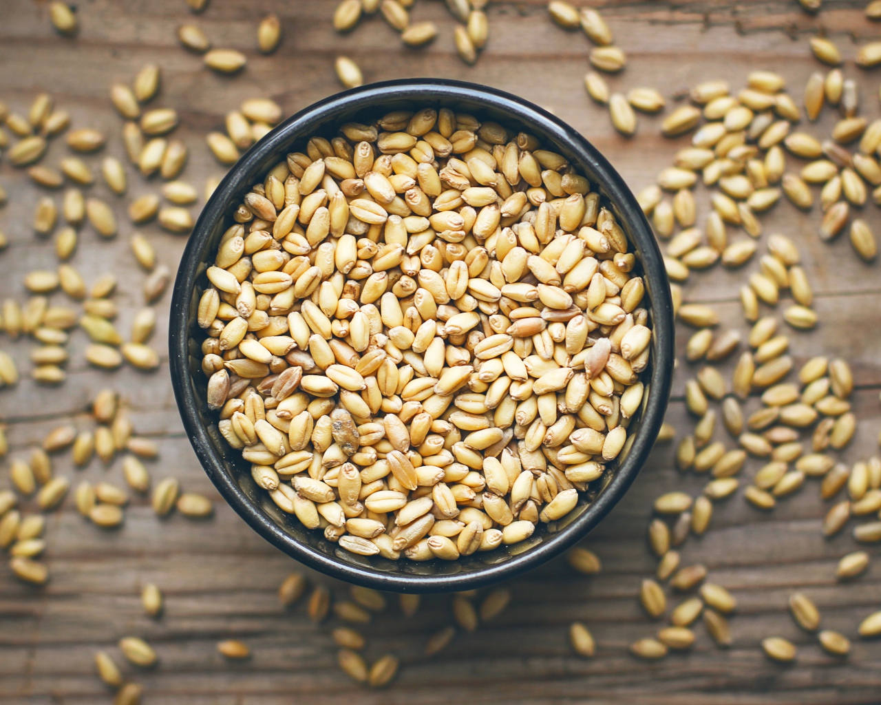 Зерна пшеницы в черной кружке на столе 