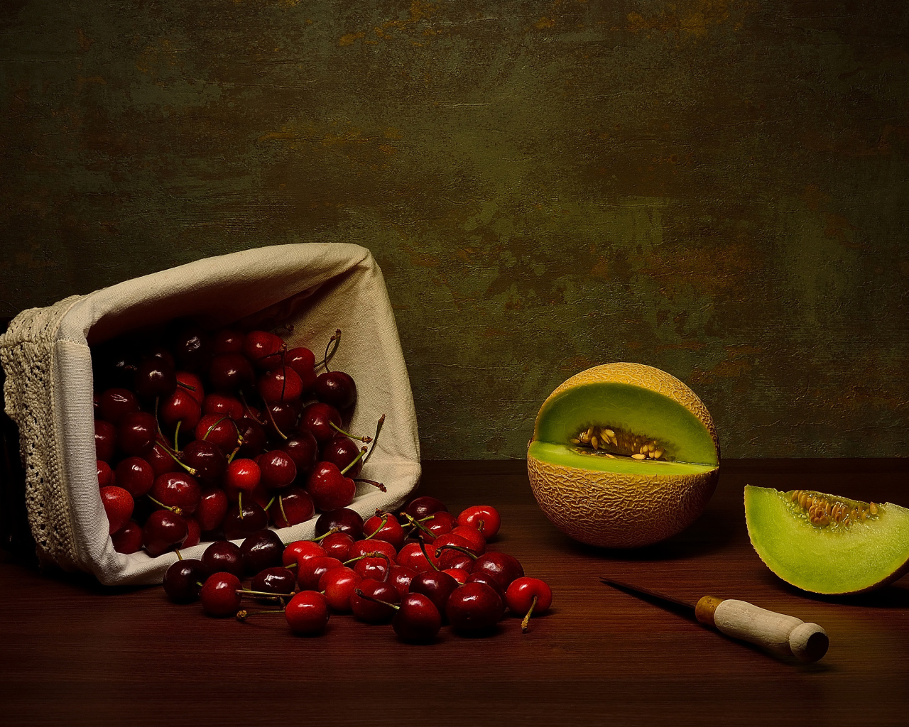 Корзина с черешнями на столе с дыней