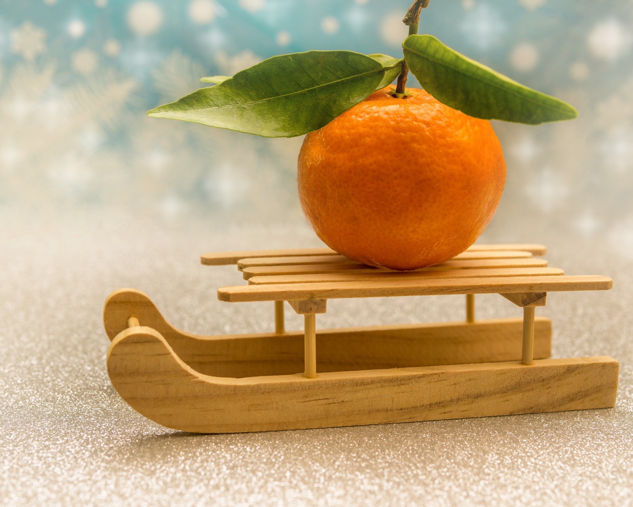 Большой оранжевый мандарин на маленьких санках