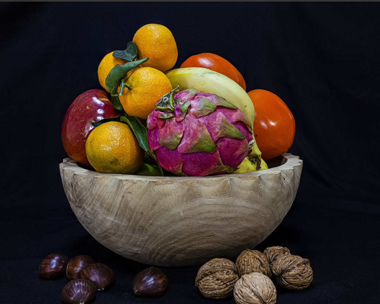 Цитрусовые фрукты в деревянной миске на черном фоне