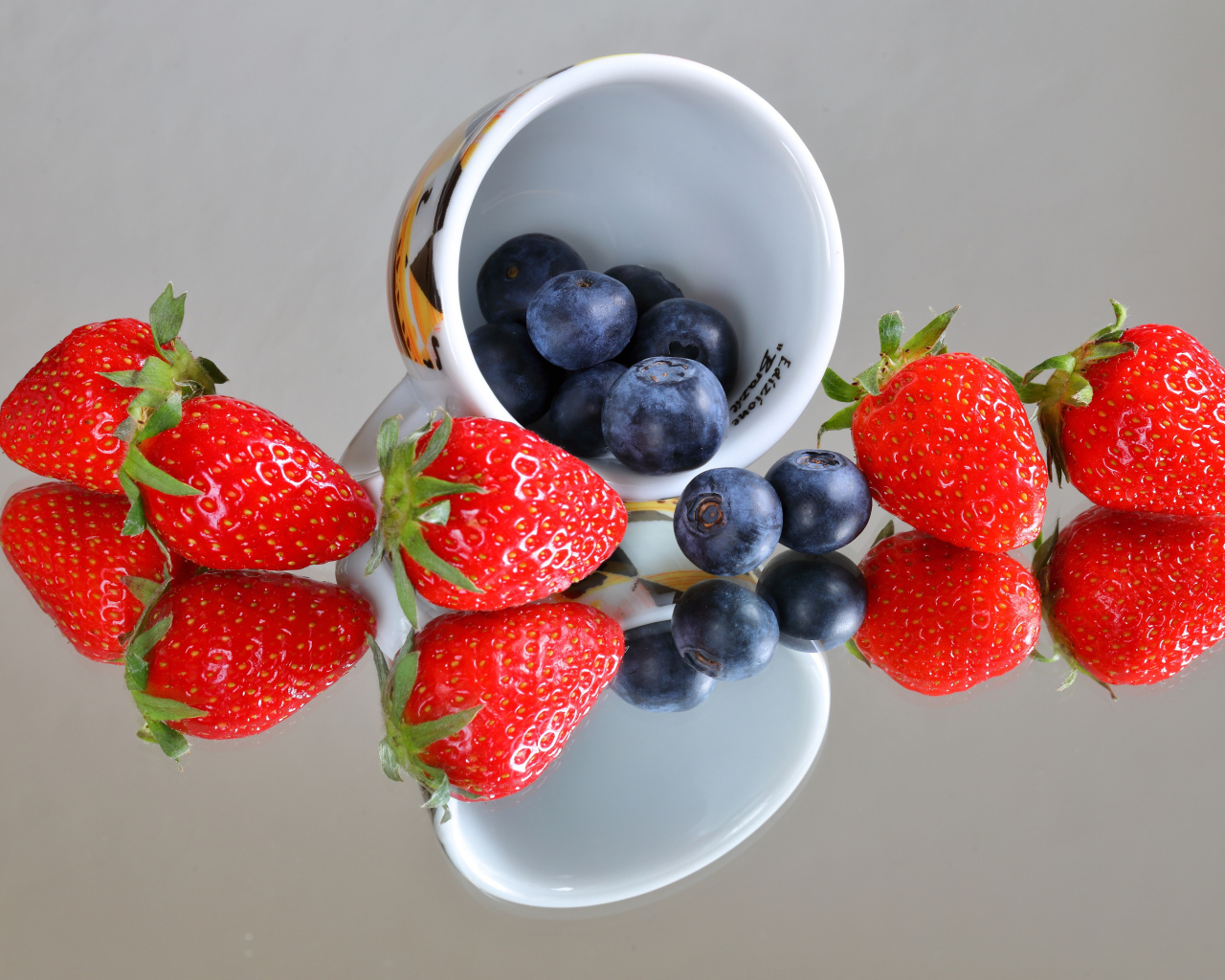 Чашка с ягодами черники и клубники на столе