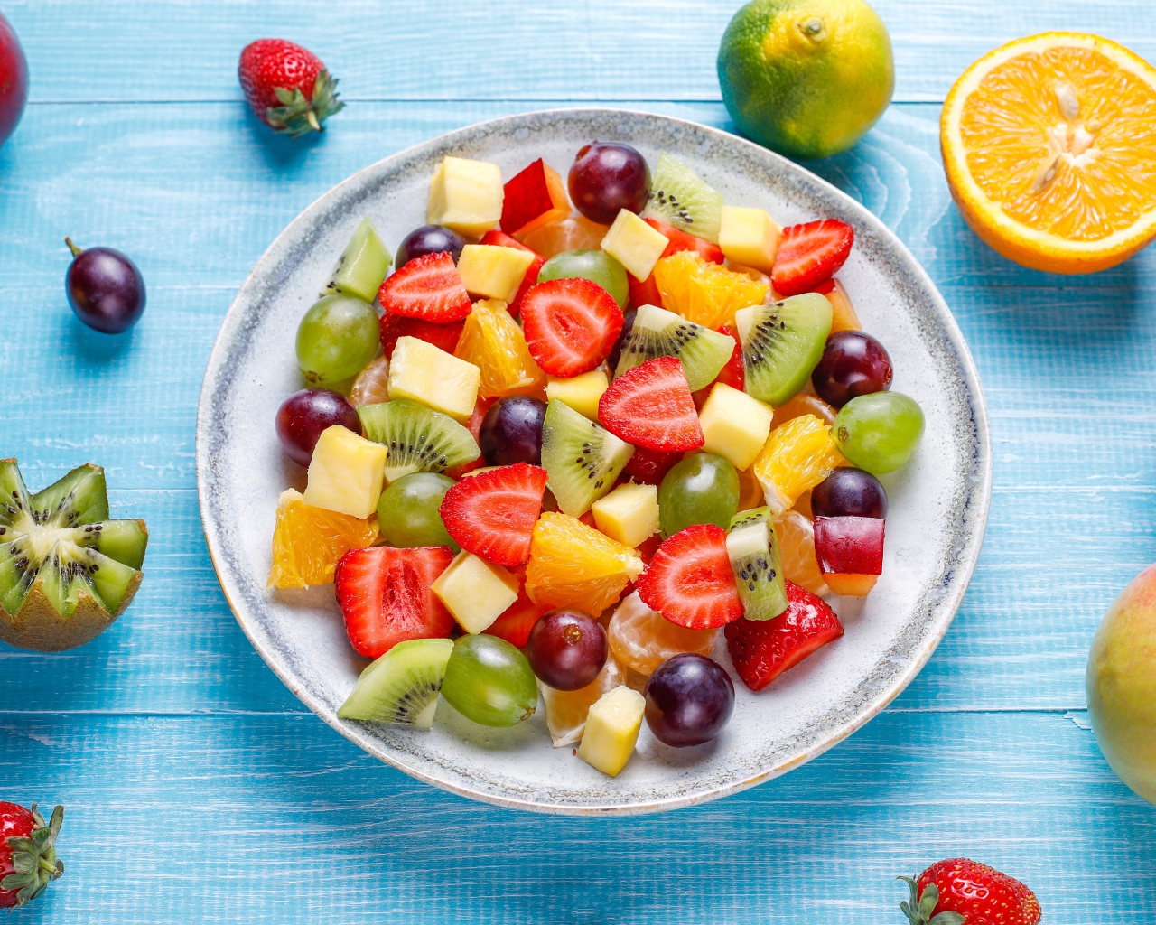 Вкусный салат из свежих овощей и ягод на голубом столе