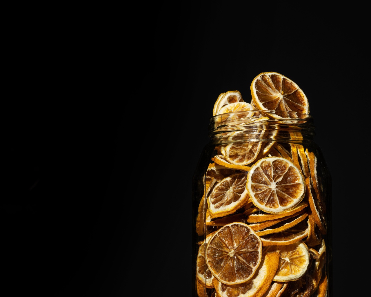 Сушеные лимоны в банке на черном фоне