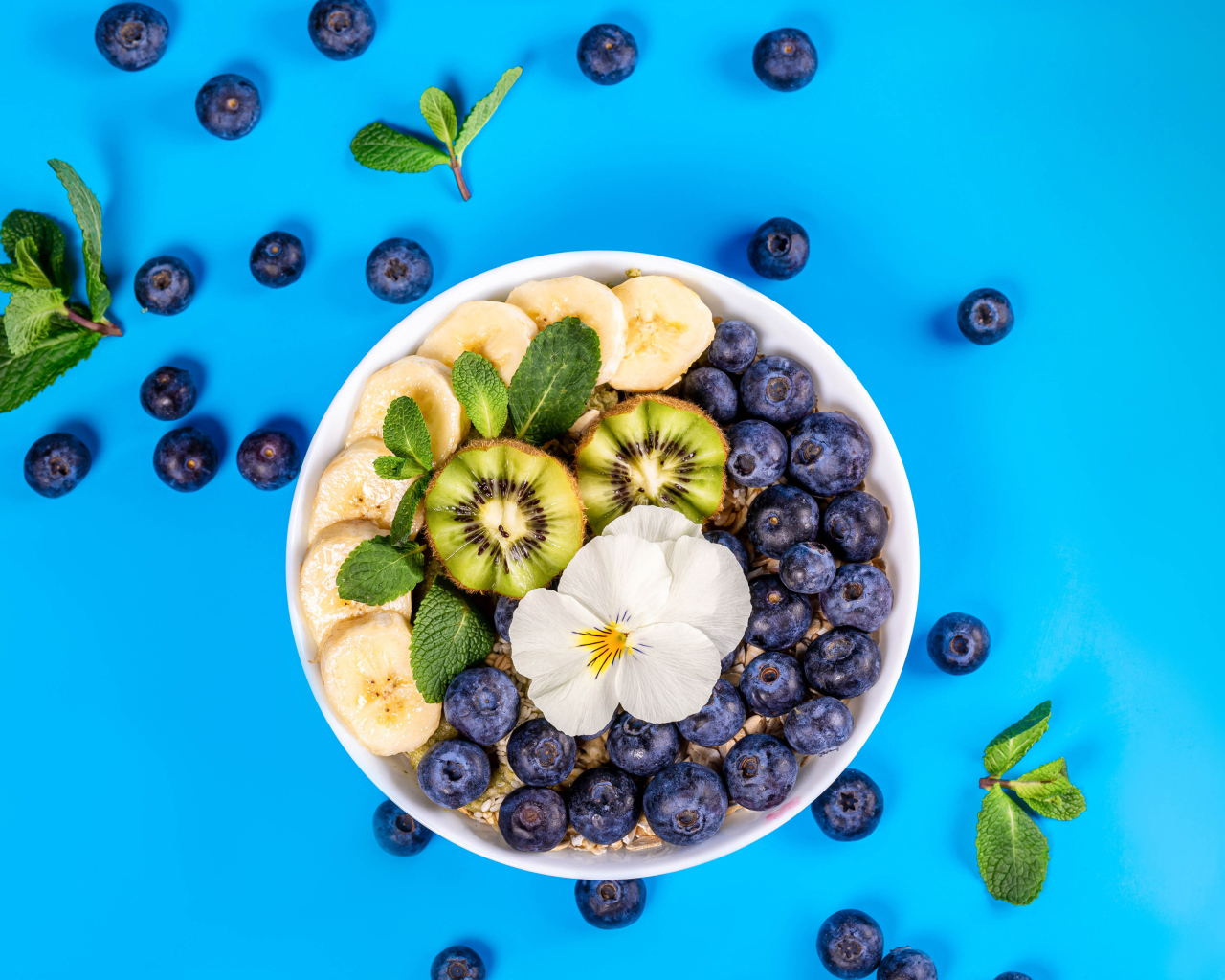 Хлопья с кусочками банана, черникой и киви на голубом фоне 