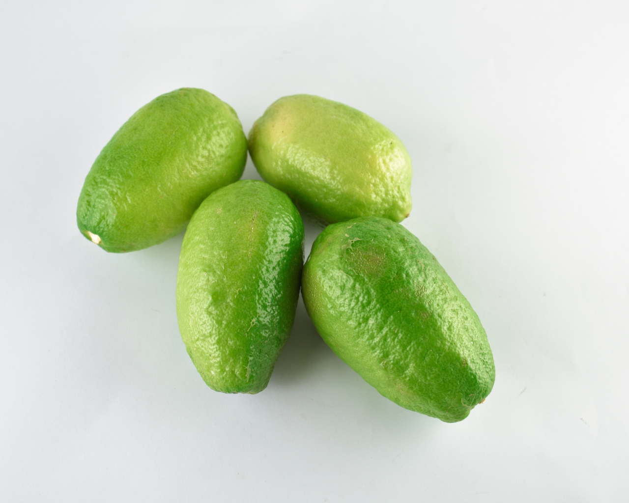 Четыре зеленых лимона на белом фоне