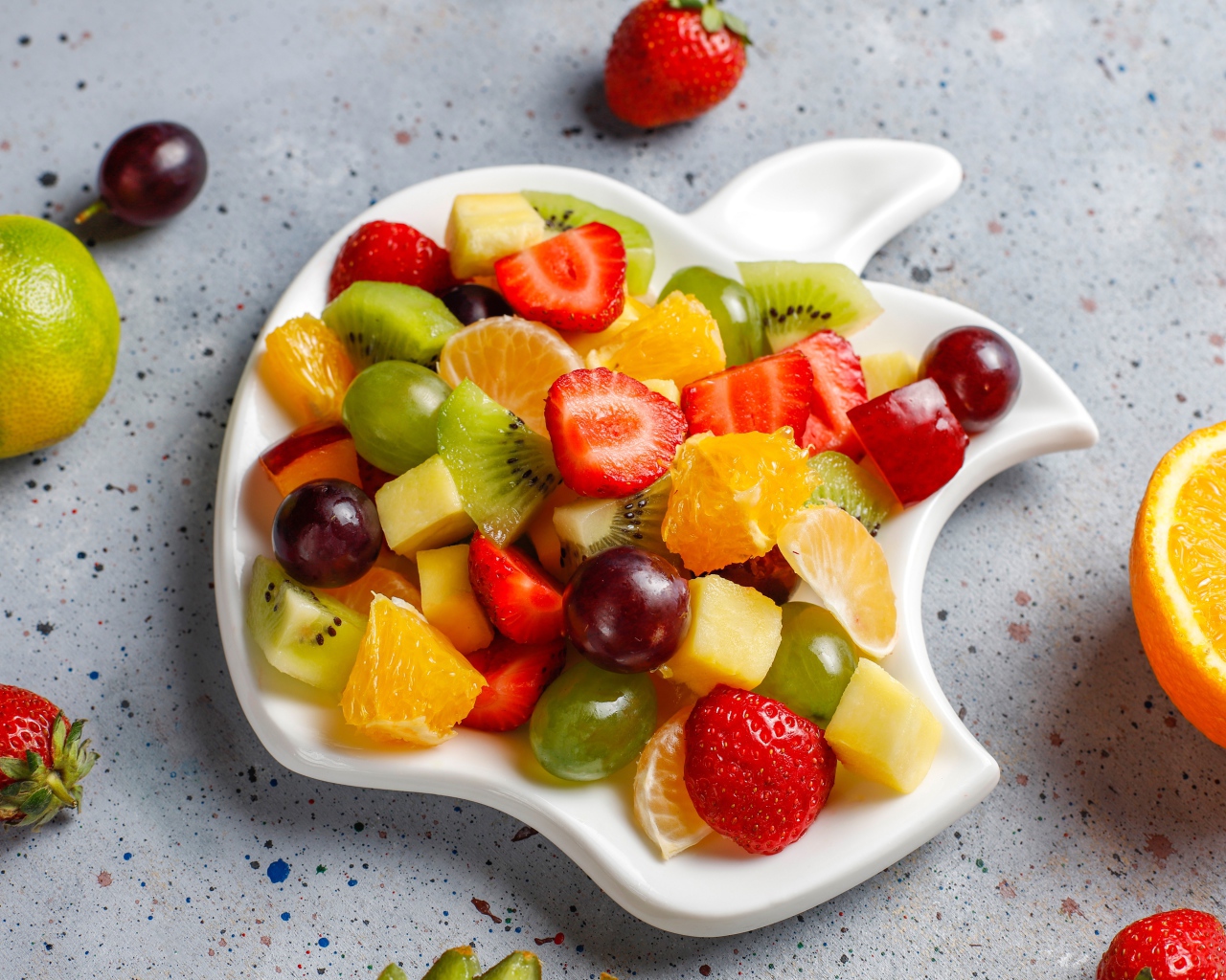 Фруктовый салат на белой тарелке на столе 