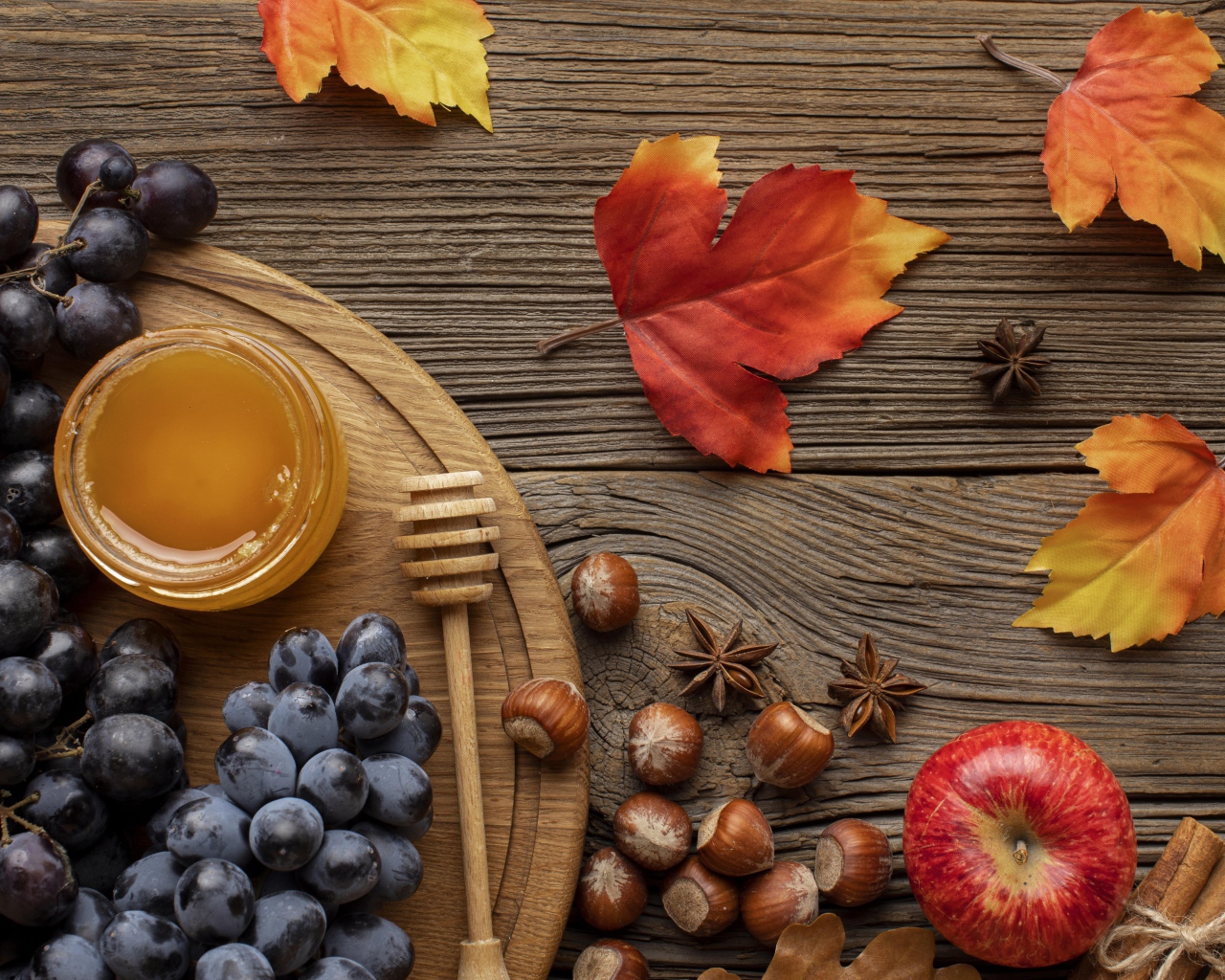 Мед на столе с виноградом, орехами и яблоками