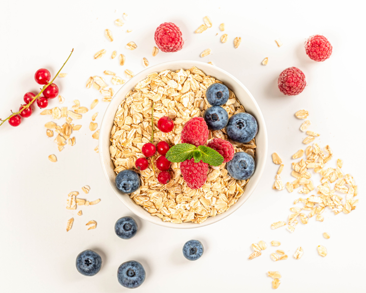 Овсяные хлопья с ягодами черники и малины на белом фоне 