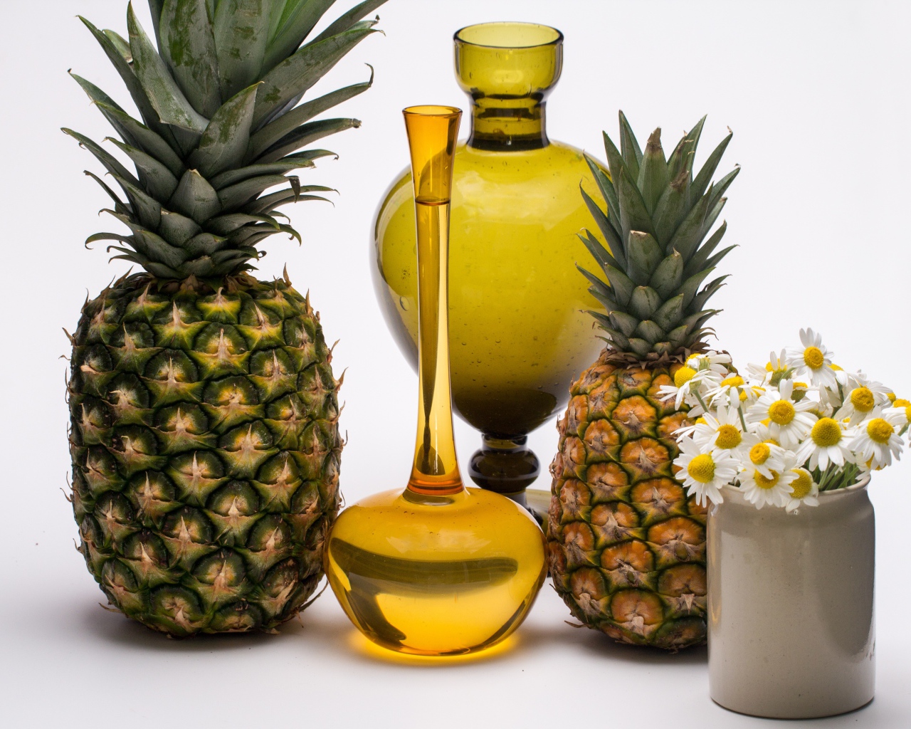 Ананасы на столе с маслом и ромашками