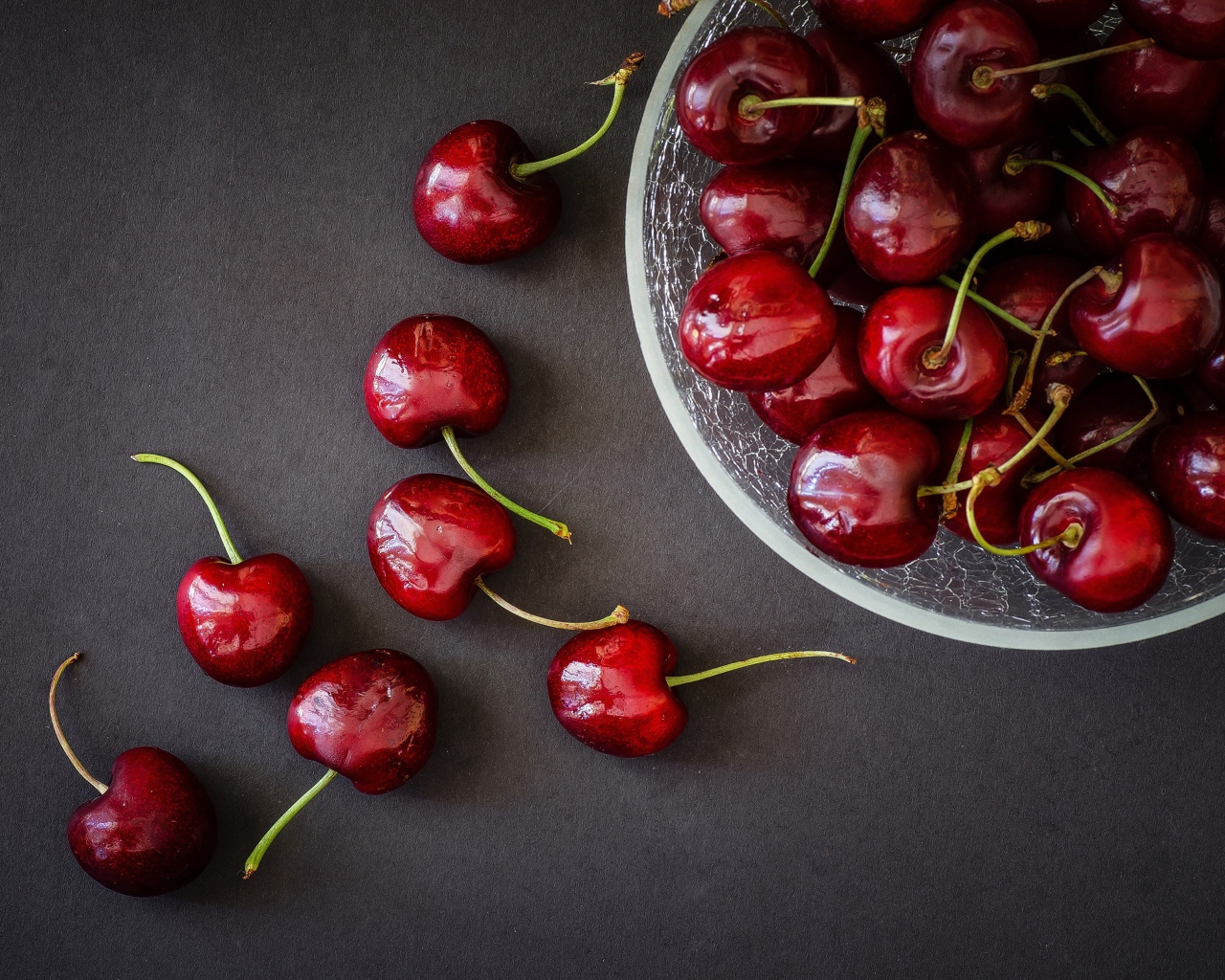 Красные черешни в миске на сером фоне