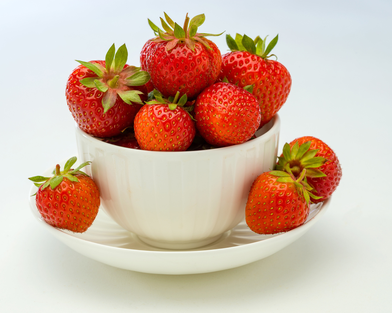 Спелая красная клубника в белой миске с блюдцем