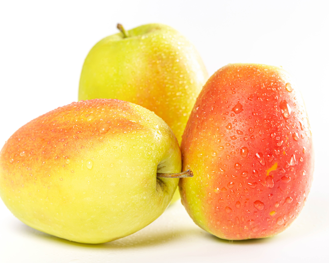Три мокрых яблока на белом фоне