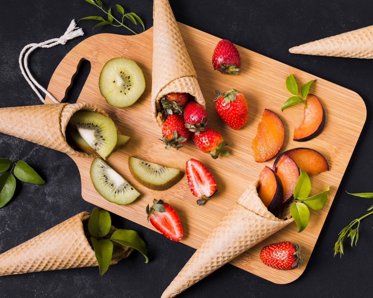 Вафельные рожки с ягодами и фруктами на доске 