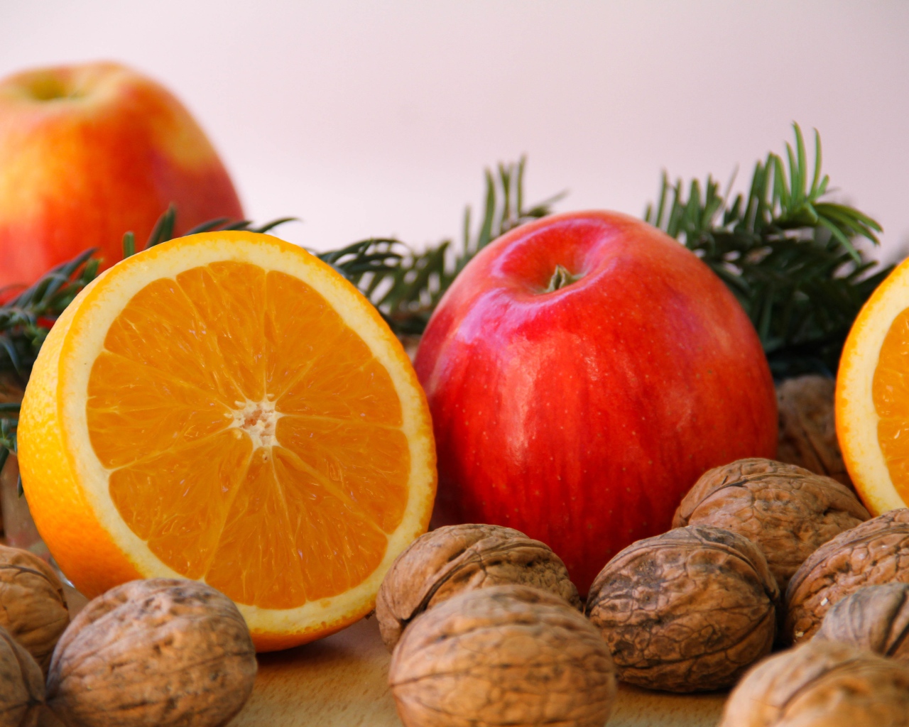 Грецкие орехи с апельсинами и яблоками на сером фоне 