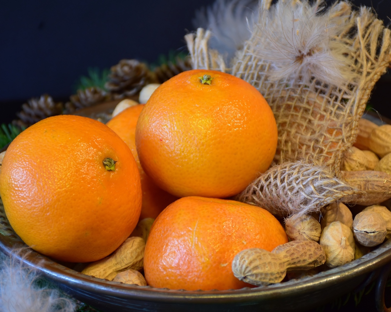 Желтые апельсины с арахисом  на тарелке