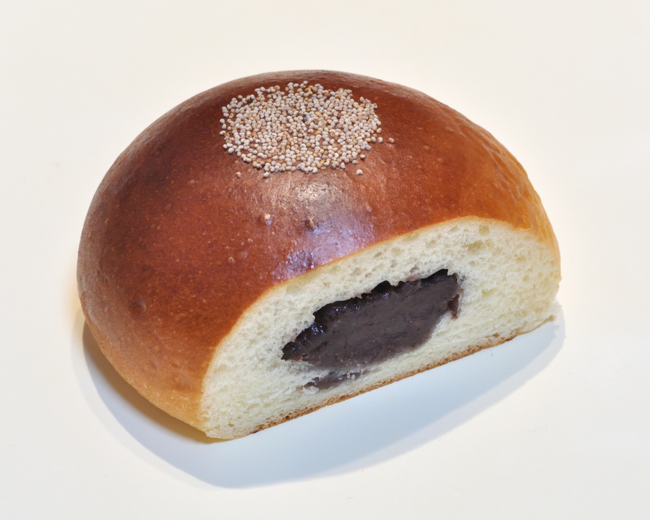 Свежая румяная булочка с вареньем на белом фоне