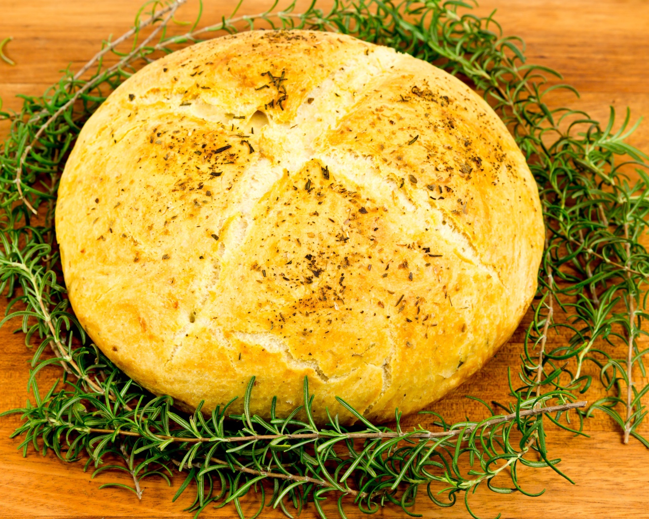 Буханка свежего ароматного хлеба с розмарином на столе