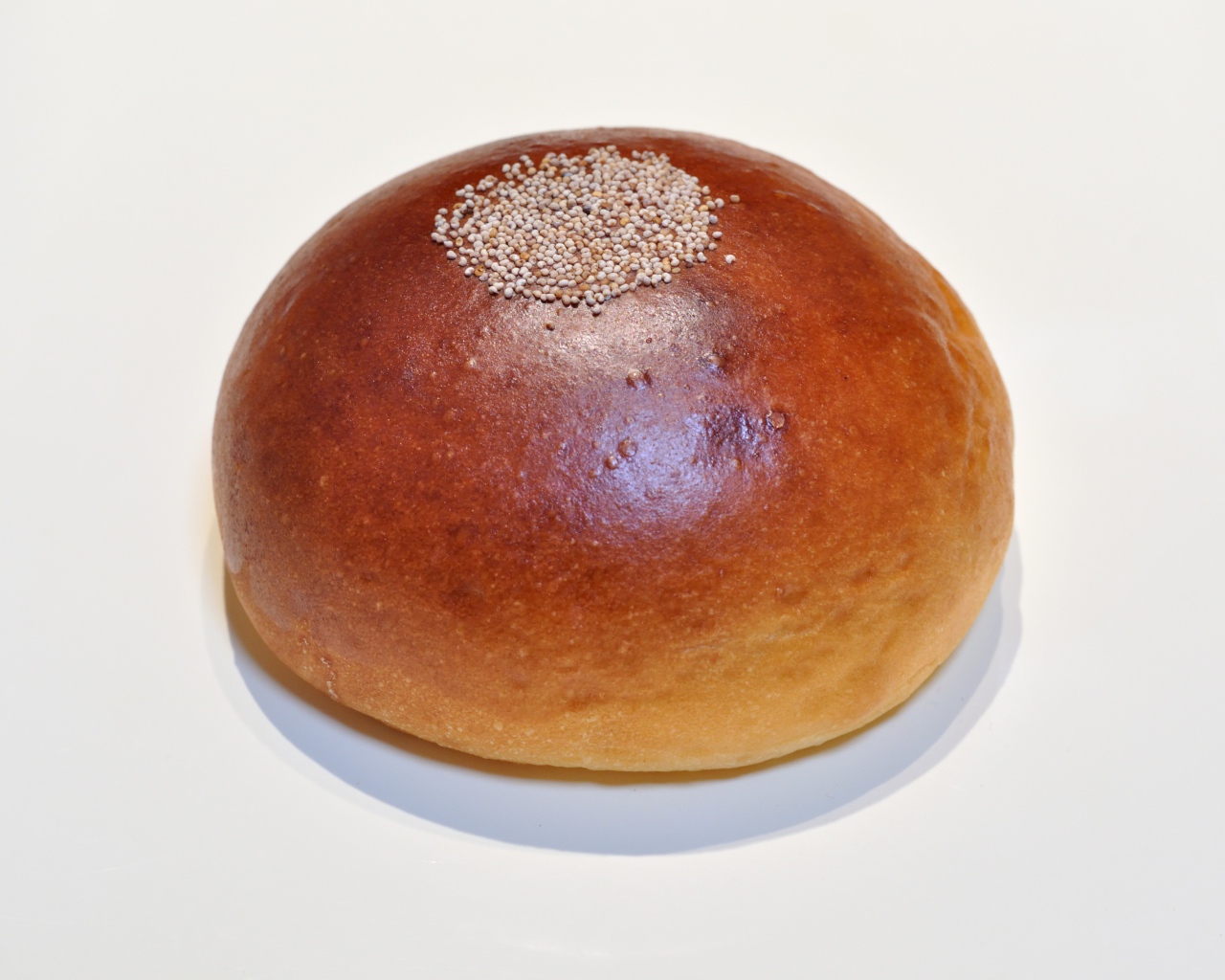 Аппетитная круглая булочка на сером фоне