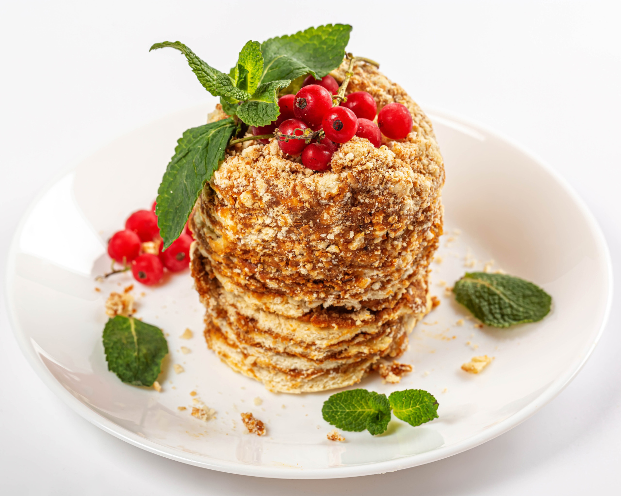 Вкусное пирожное со сгущенкой и ягодами красной смородины на белом фоне