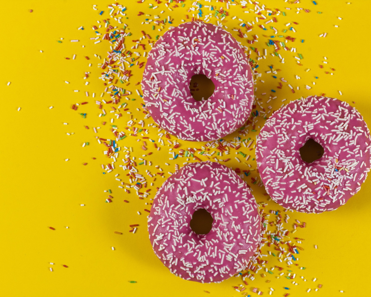 Пончики с розовой глазурью на желтом фоне