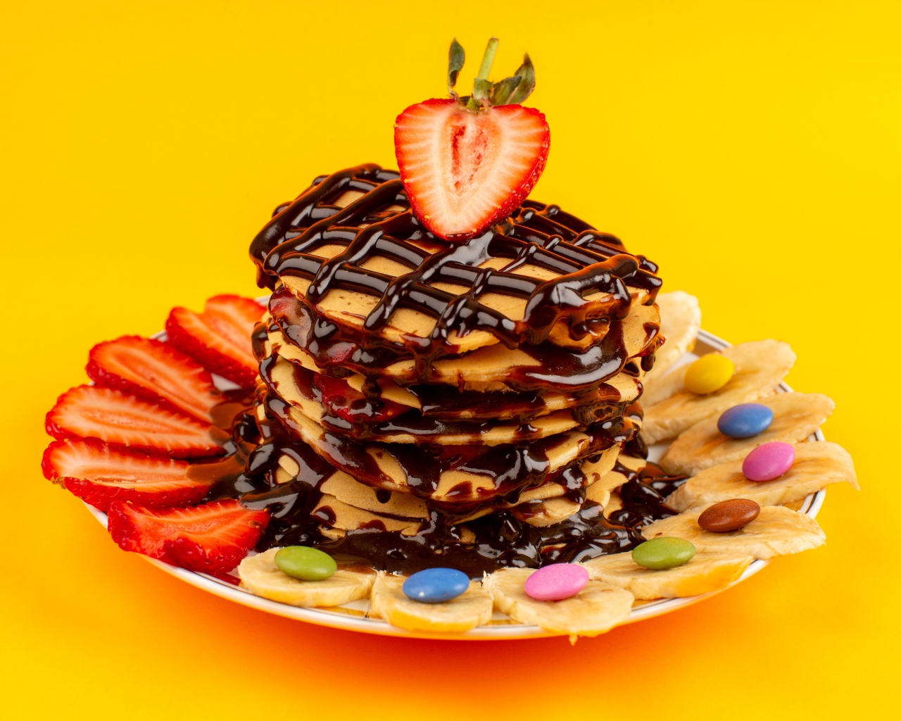 Оладьи с шоколадом, клубникой и бананом на желтом фоне 