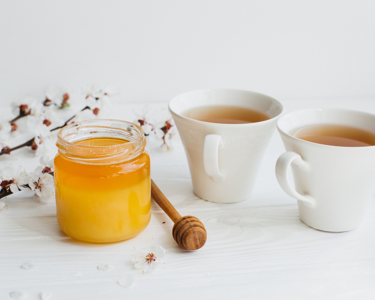 Мед на столе с чаем и цветами абрикоса