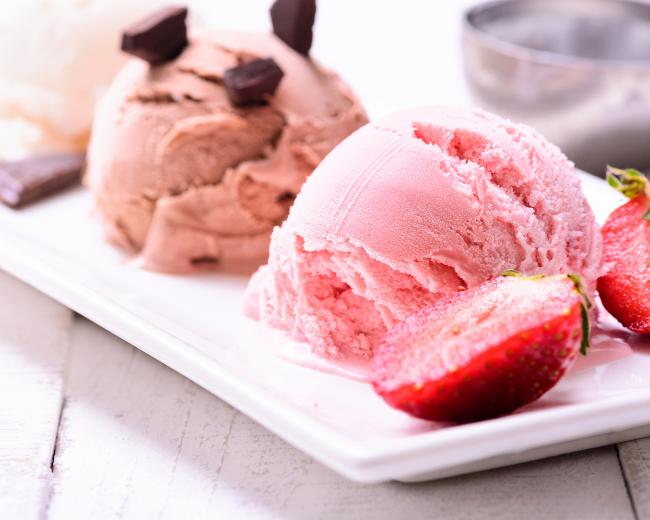 Шарики мороженого на большой белой тарелке с клубникой