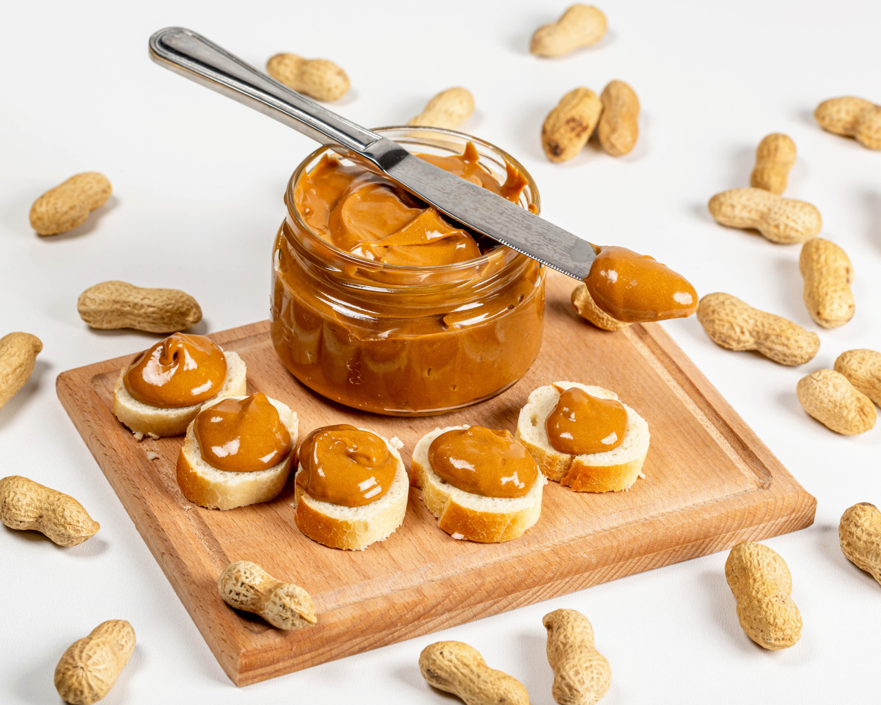 Ореховая паста на столе с батоном и арахисом