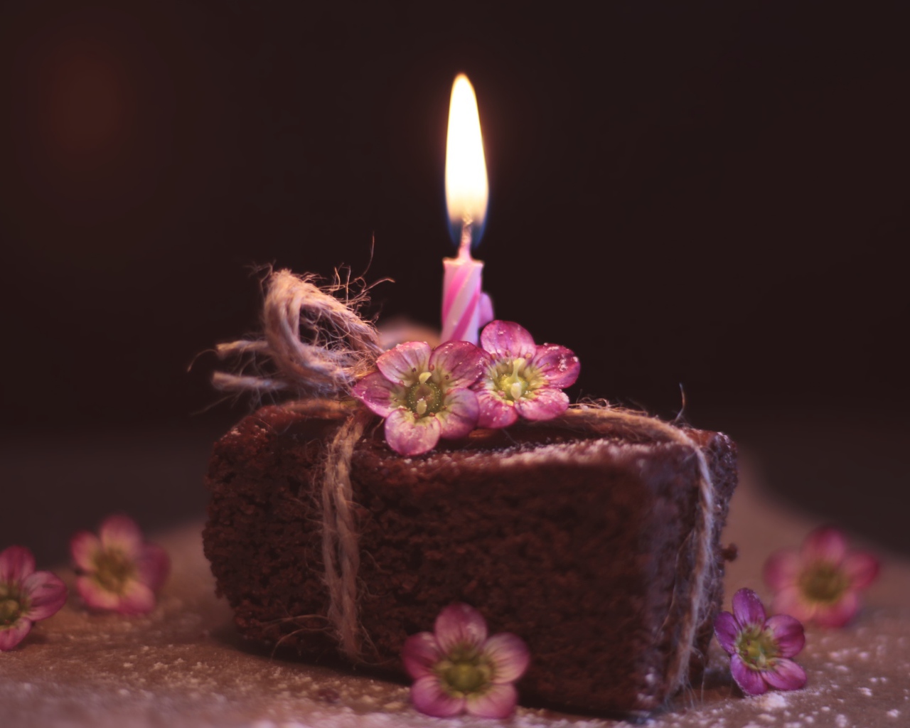 Кусок торта на столе с розовыми цветами и свечкой