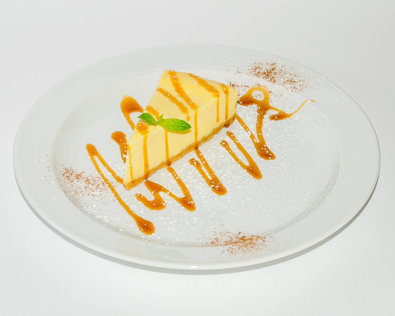 Кусок чизкейка с сиропом на большой белой тарелке 