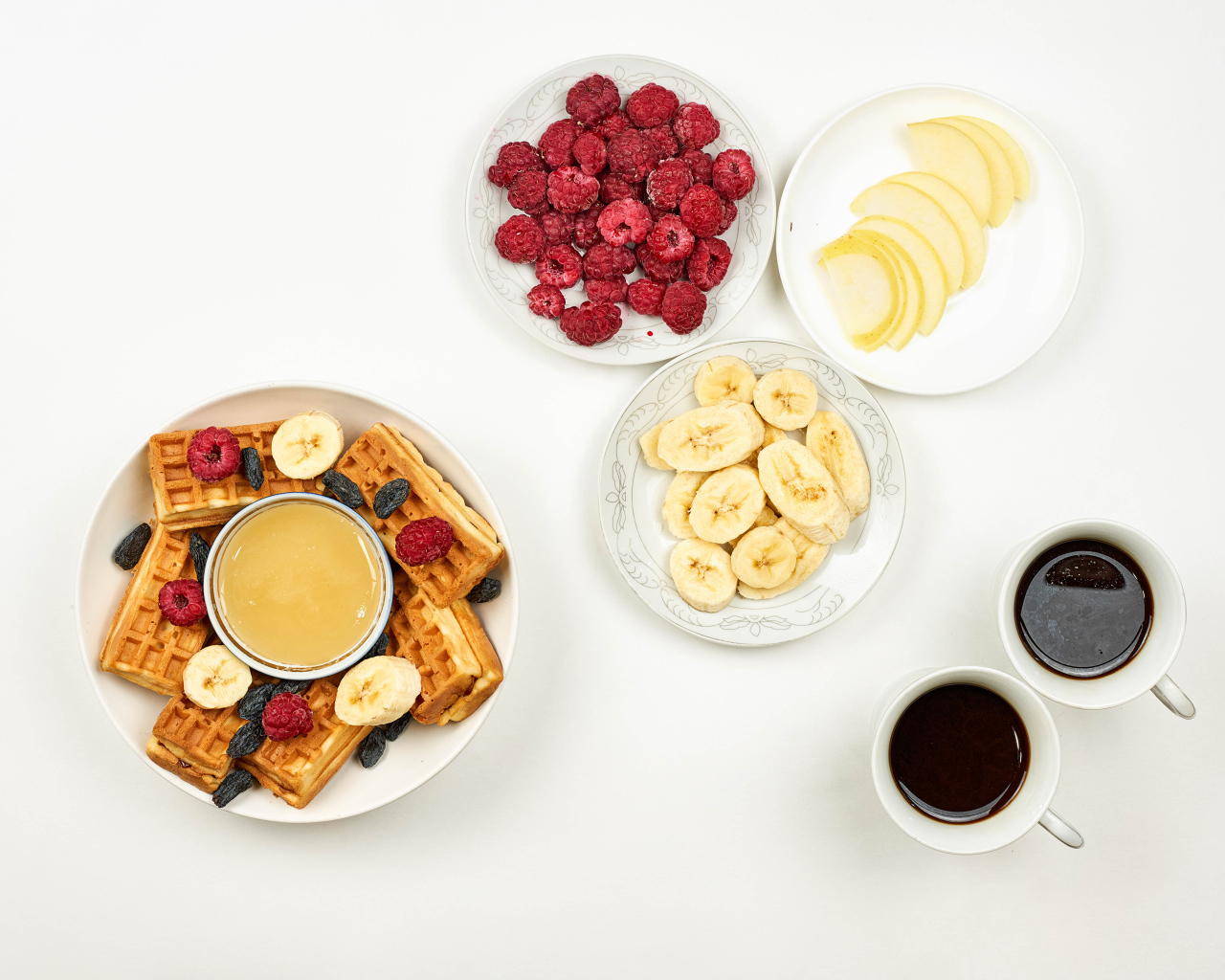 Сладкие вафли с малиной и бананами на столе  с кофе