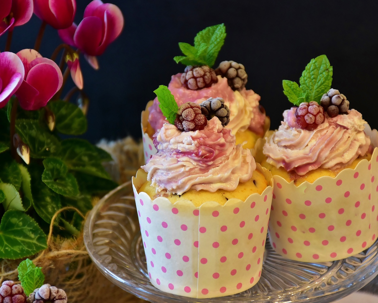 Три кекса с кремом на столе с цветами 