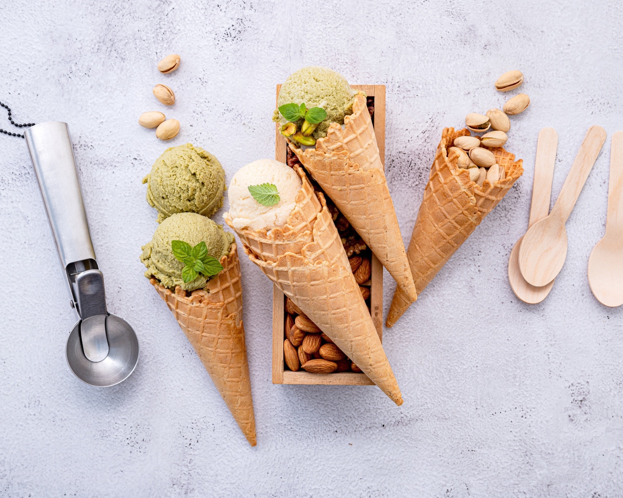Вафельные рожки на столе с фисташковым мороженым и миндалем 