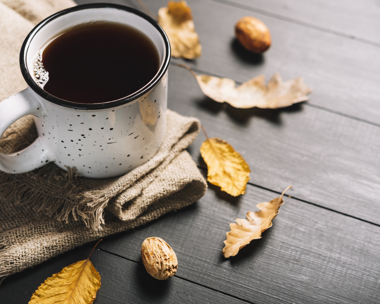 Кружка кофе на столе с листьями и пледом