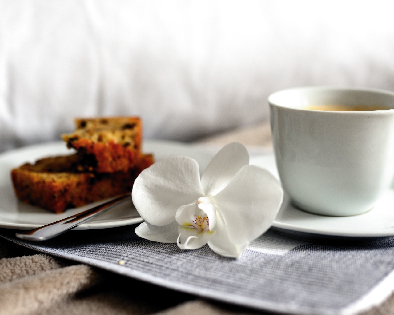 Чашка кофе на столе с цветком орхидеи и кусочками кекса 