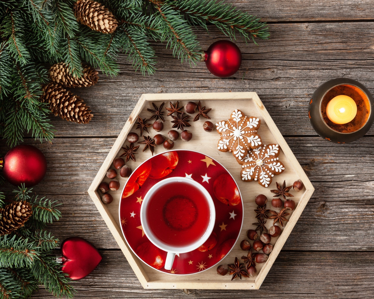 Чашка чая с печеньем и орехами на столе с еловой веткой