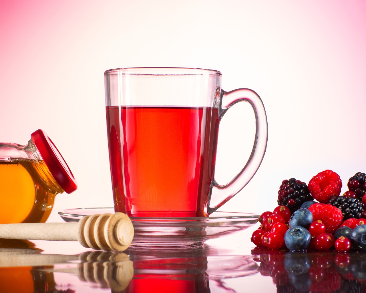 Чашка чая с медом на столе с ягодами