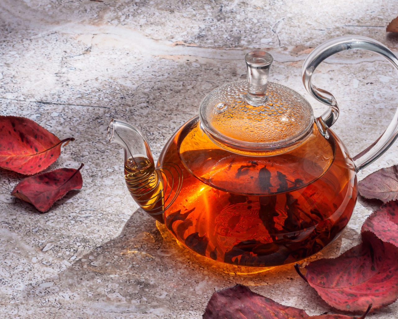 Стеклянный чайник на столе с листьями