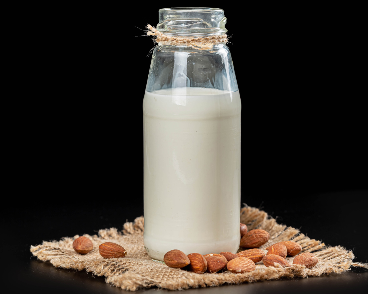 Молоко с миндалем на черном фоне
