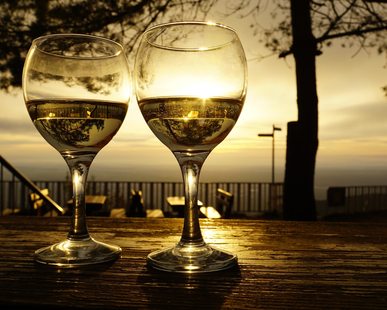 Два бокала белого вина на столе в лучах солнца