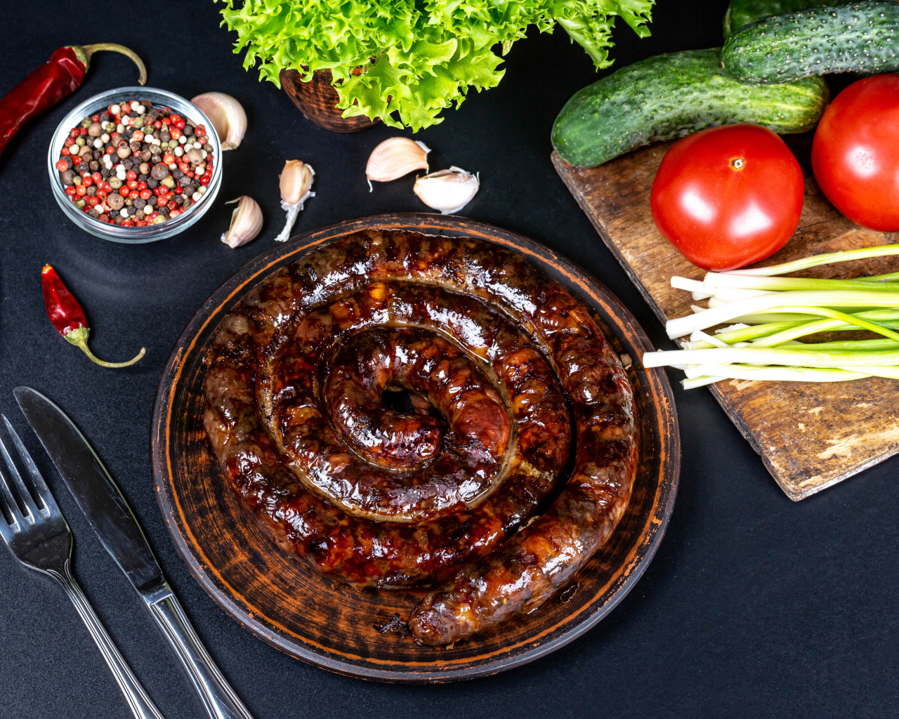 Аппетитная домашняя колбаса на столе со специями и овощами