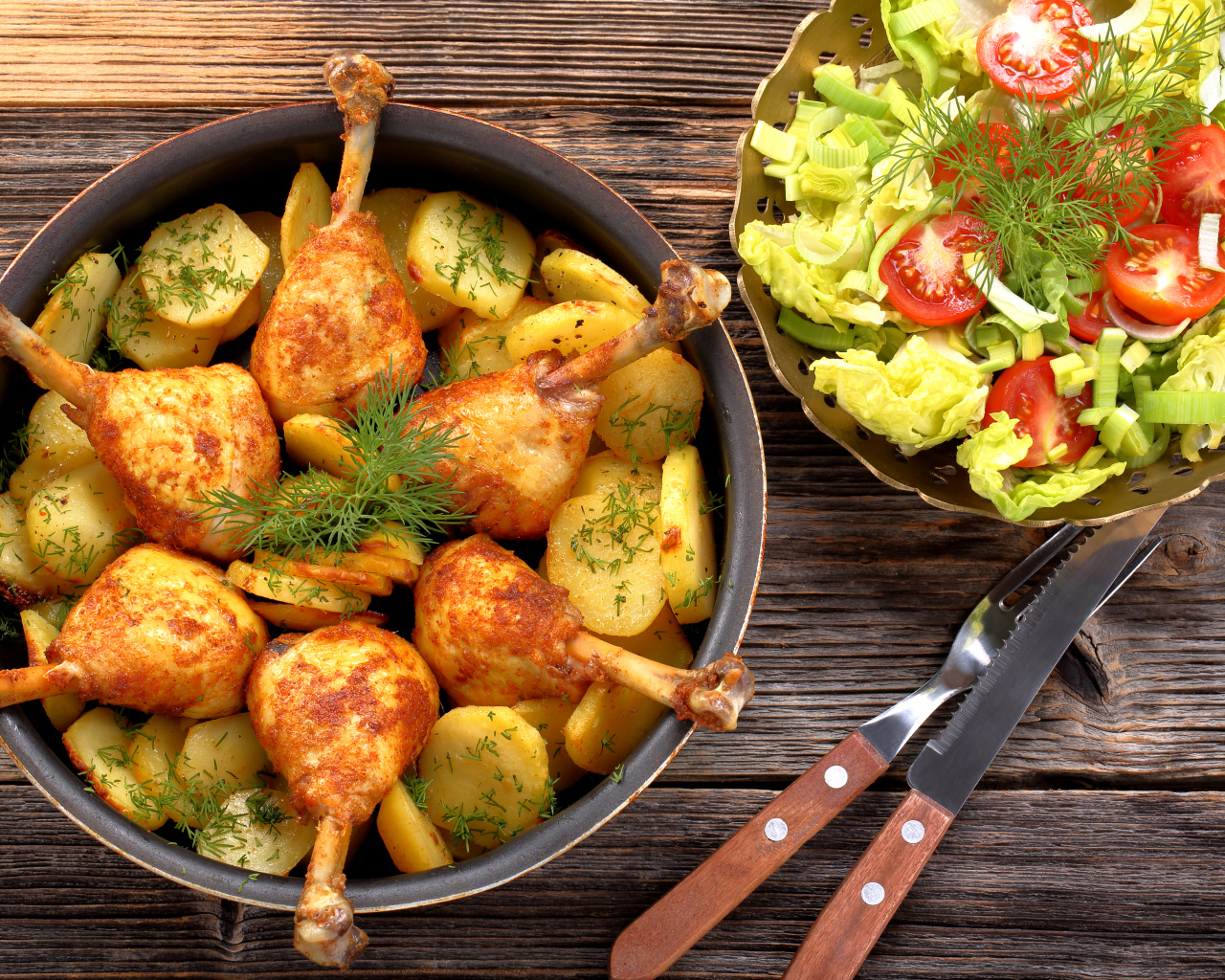 Fried chicken legs with potatoes on a table with salad