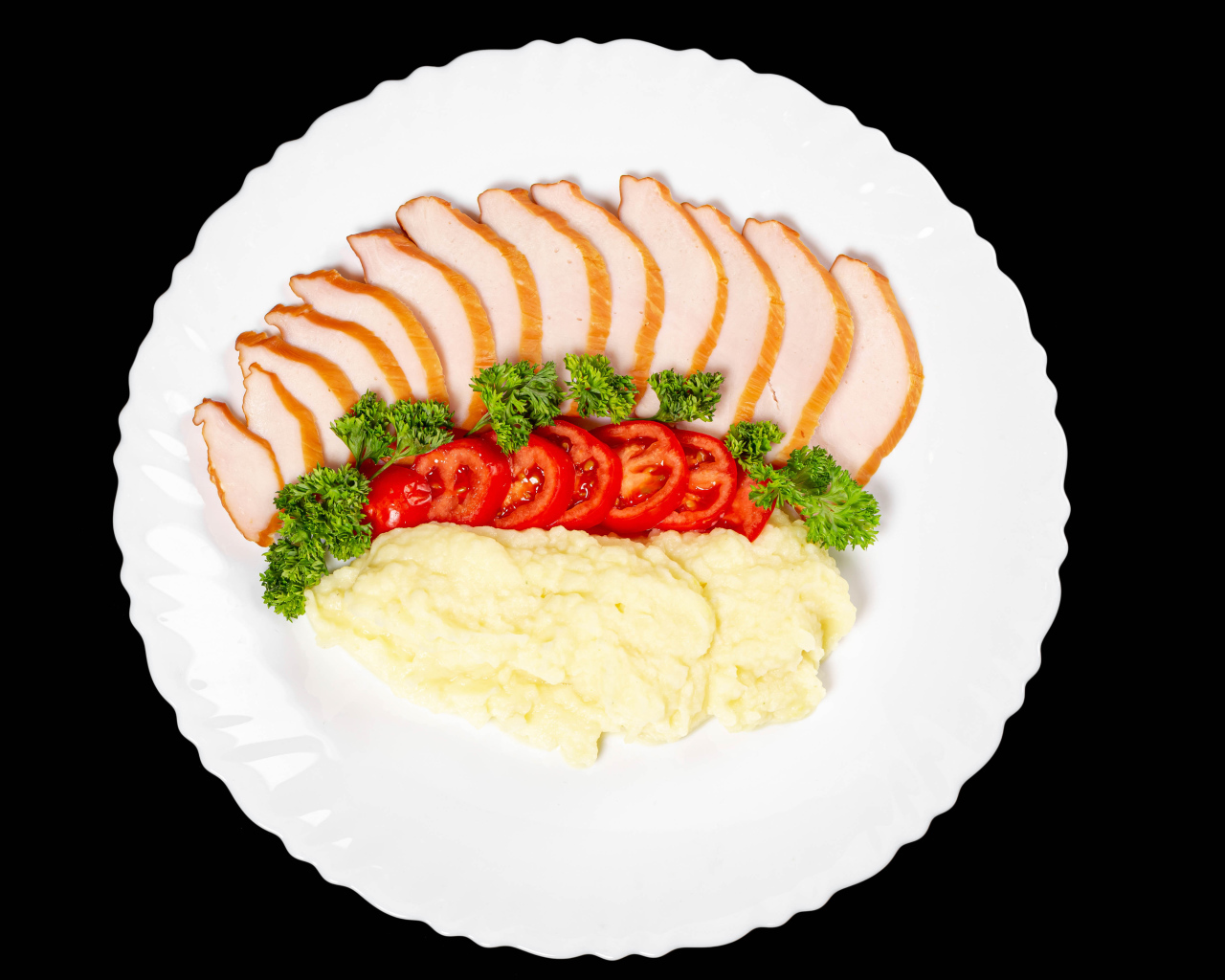 Ham on a large white plate with potatoes and tomatoes