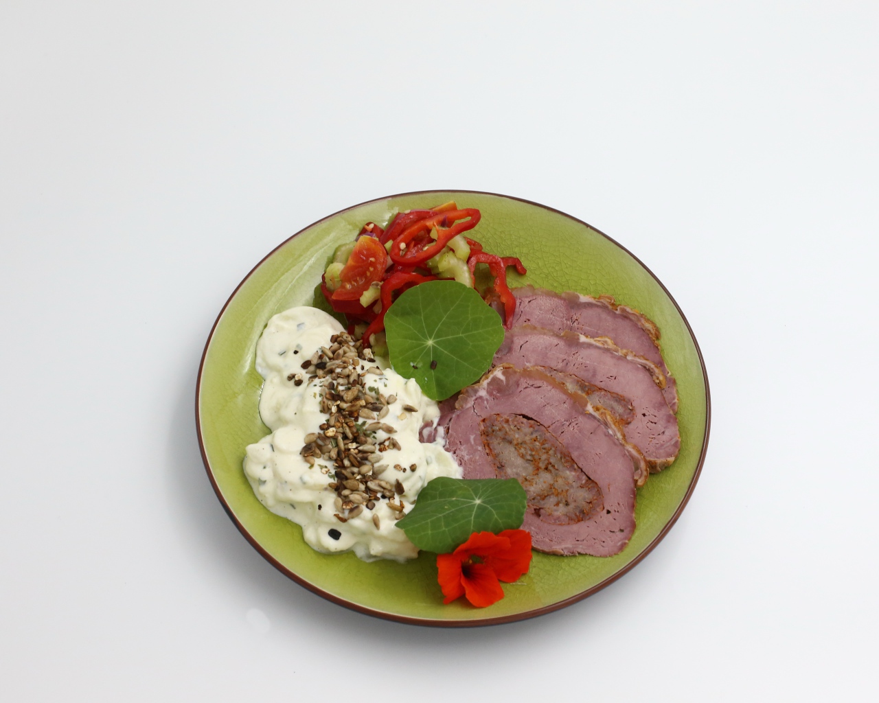 Мясо с соусом и овощами на тарелке на сером фоне