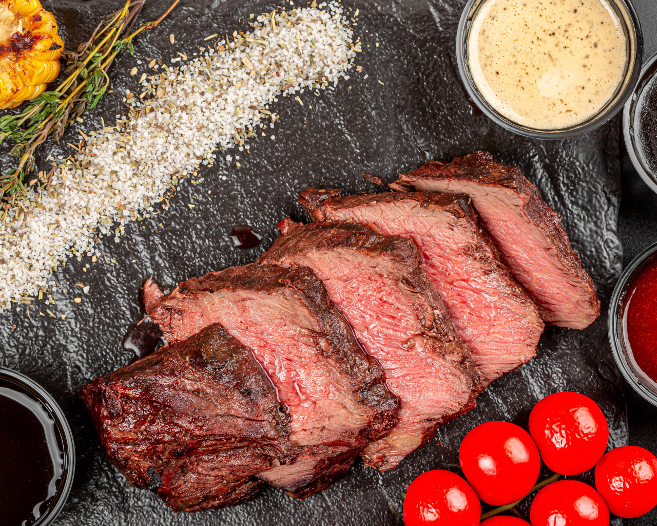 Мясо с помидорами и соусами на доске 