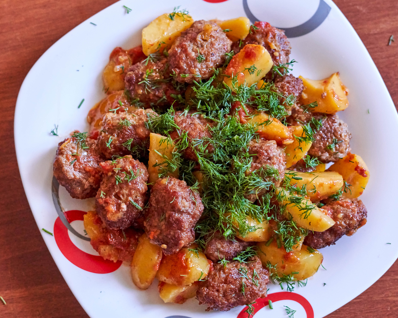 Meatballs with potatoes and dill on a white plate