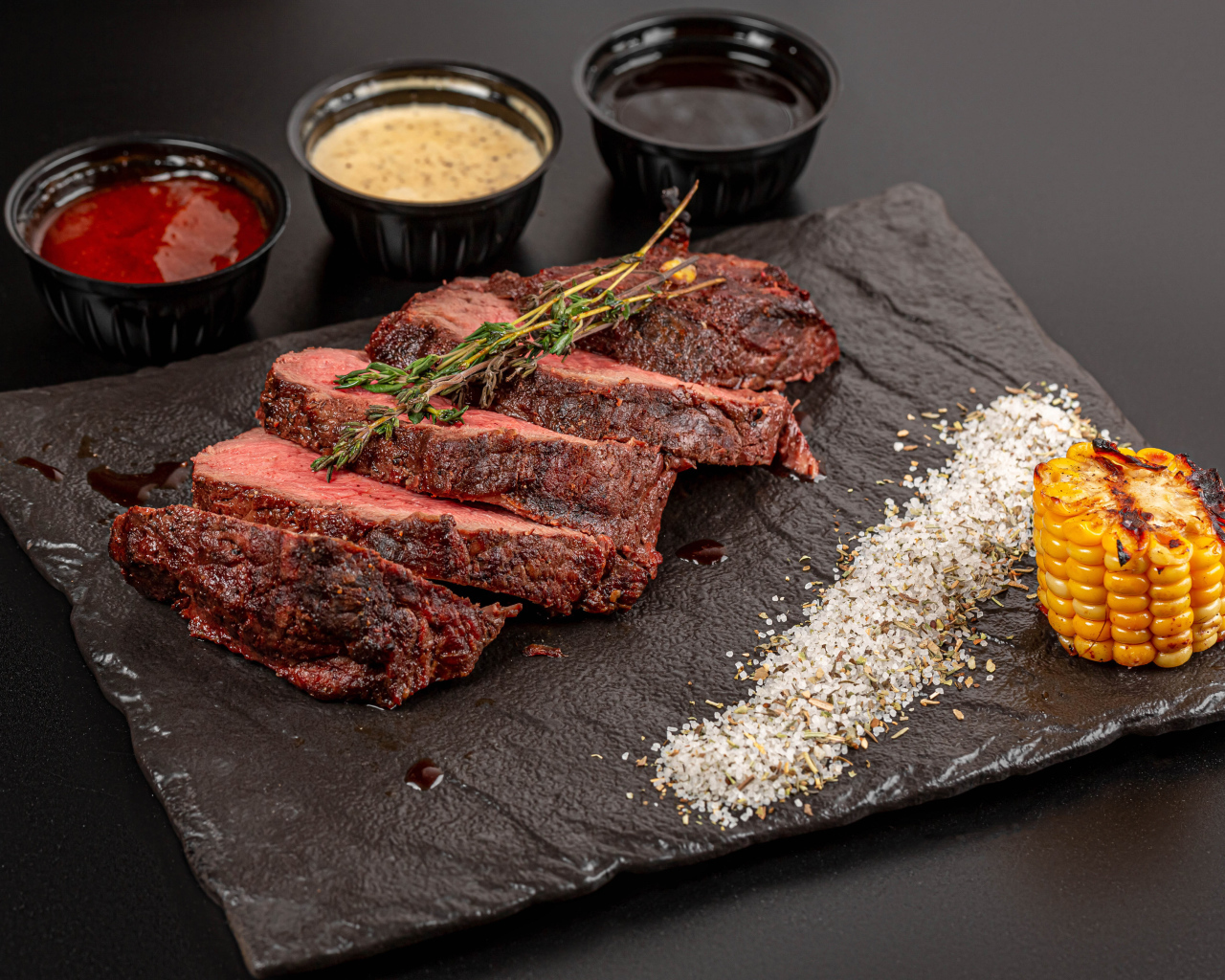 Кусок запеченного мяса на доске с кукурузой и специями 