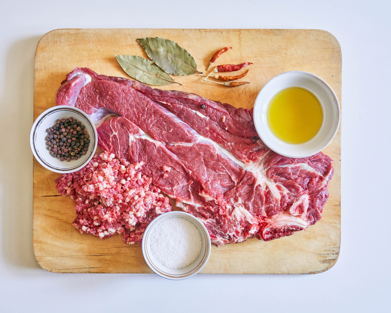 Кусок мяса со специями и оливковым маслом на доске 