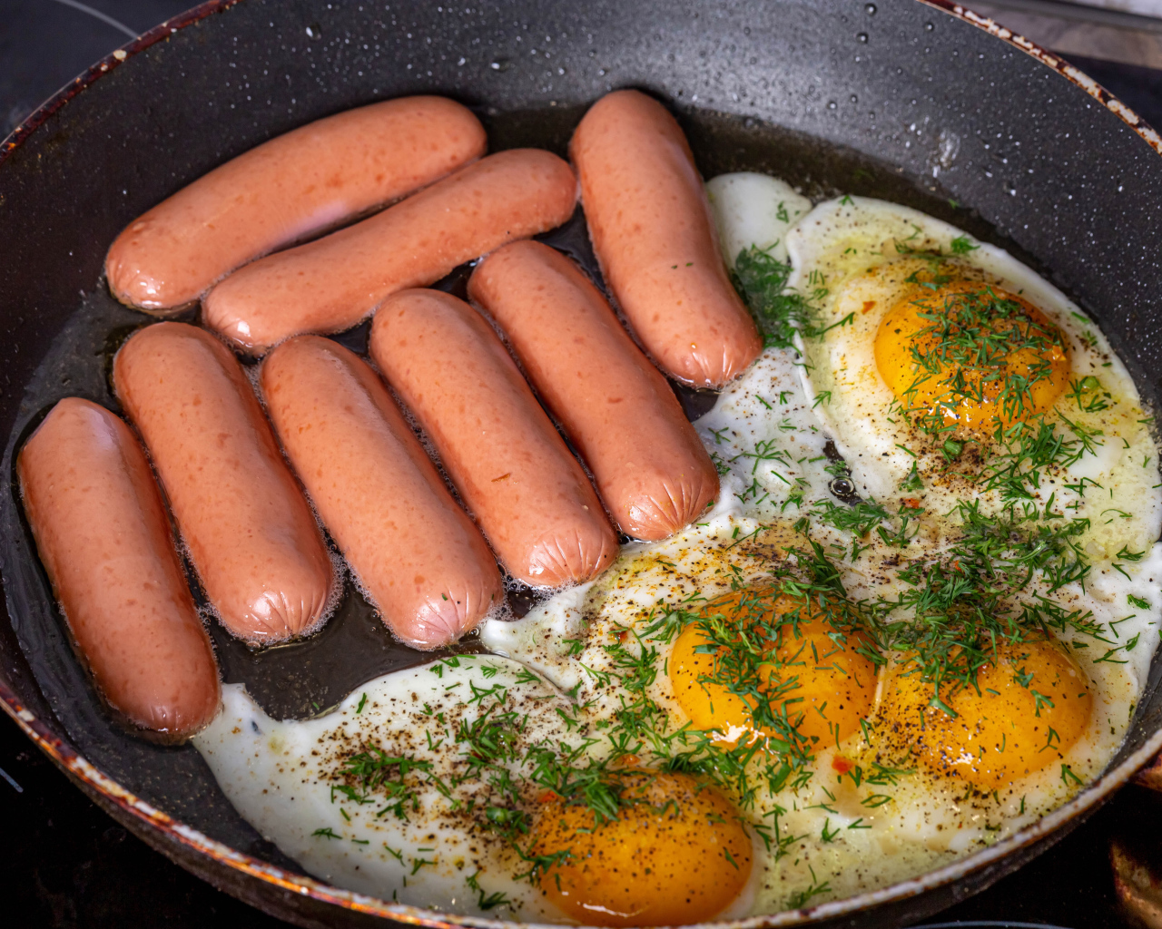 Сосиски с яичницей на сковороде