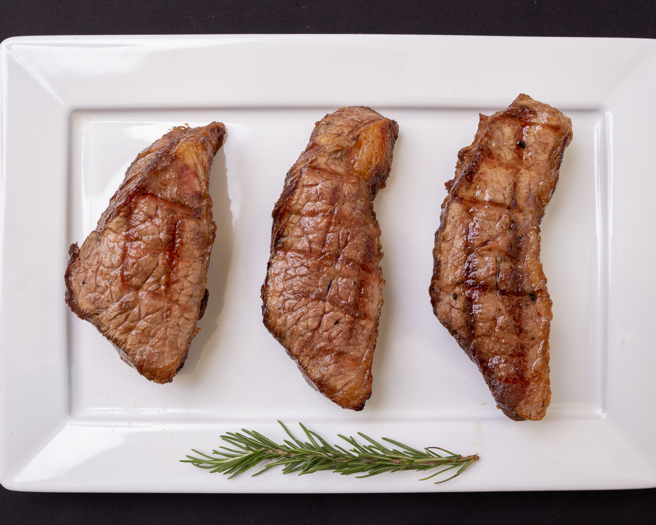 Три куска жареного мяса на большой белой тарелке